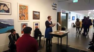 A woman in a gallery space reading while standing at a desk
